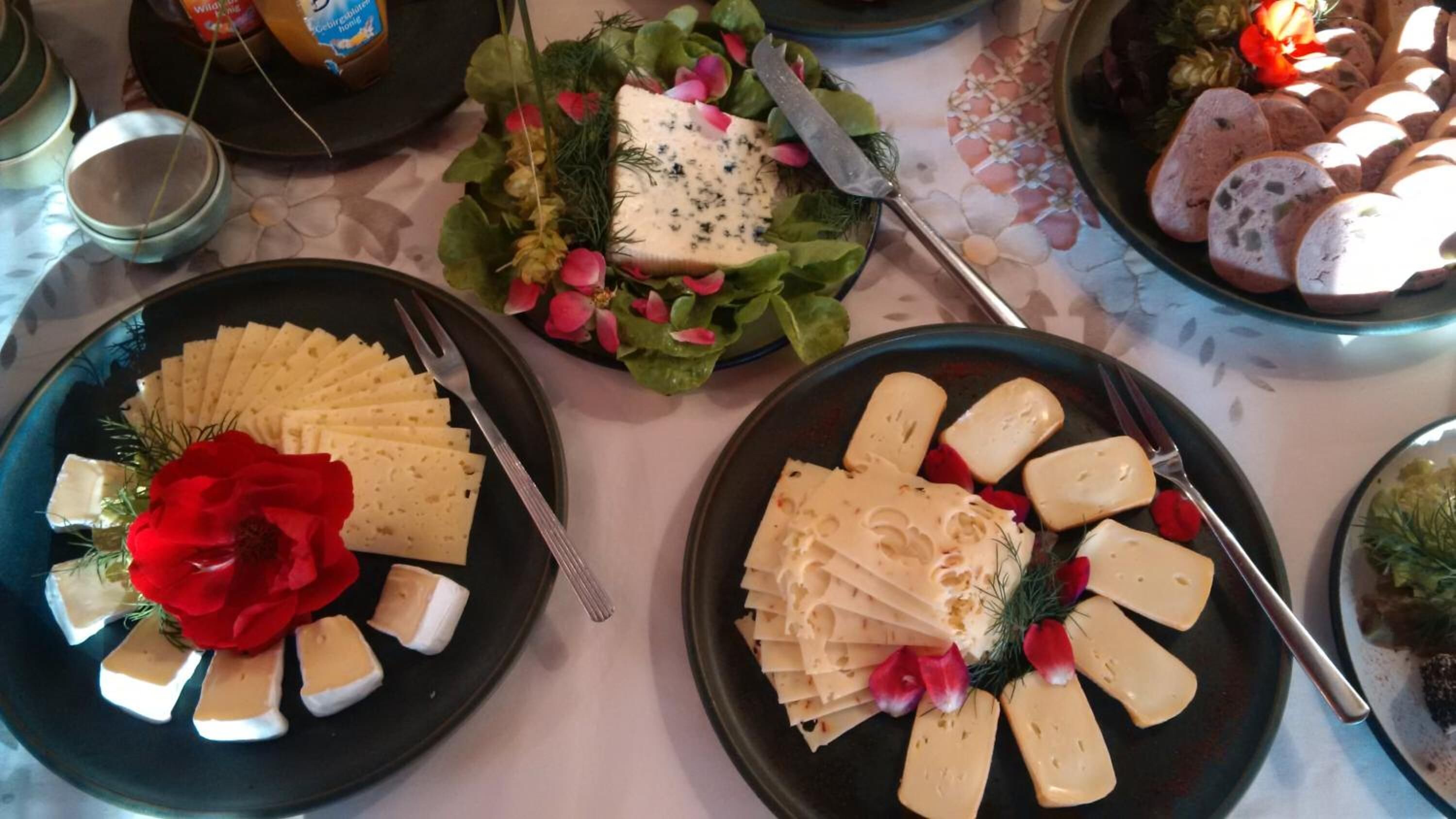 A table with plates of cheese and flowers.