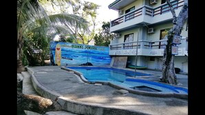 A swimming pool with a mural of a forest and ocean, surrounded by concrete steps and palm trees. - Nature Green Forest Resort (Baler)