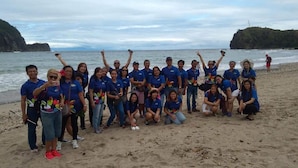 A group of people on a beach with a rocky coastline in the background. - Nature Green Forest Resort (Baler)