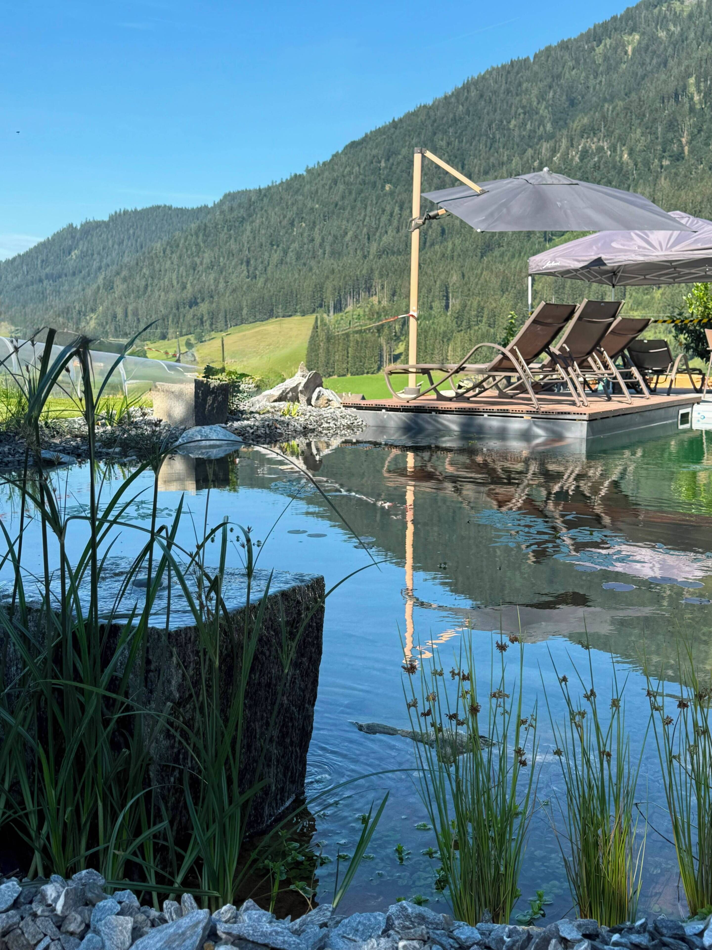 A lakeside view with a boat dock, lounge chairs, and a wooden deck.