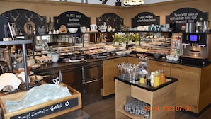 A buffet area with various food items, a coffee station, and a display of glassware.