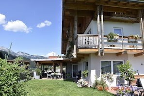 A chalet with a wooden balcony, a patio with outdoor furniture, and a view of mountains. - Landhotel Anna (Sankt Martin am Tennengebirge)