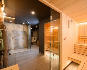 Un sauna moderno con paredes de vidrio, bancos de madera y una pared de piedra.