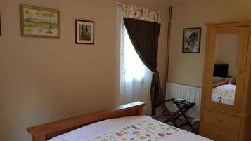 A bedroom with a wooden bed, a wooden dresser, a chair, and a window with curtains.