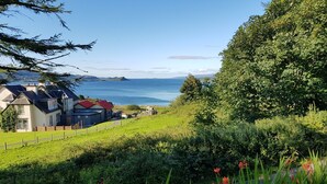 Uma propriedade costeira com vista para o mar, um jardim murado e um edifício com telhado vermelho.