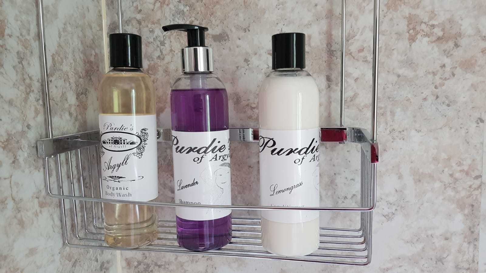 A bathroom shelf with three bottles of Purdie of Argyl body wash in different scents.