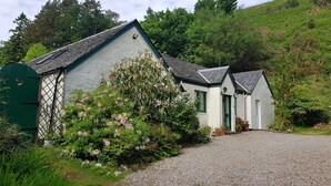 Uma casa de dois andares com entrada por um caminho de brita e um portão verde.