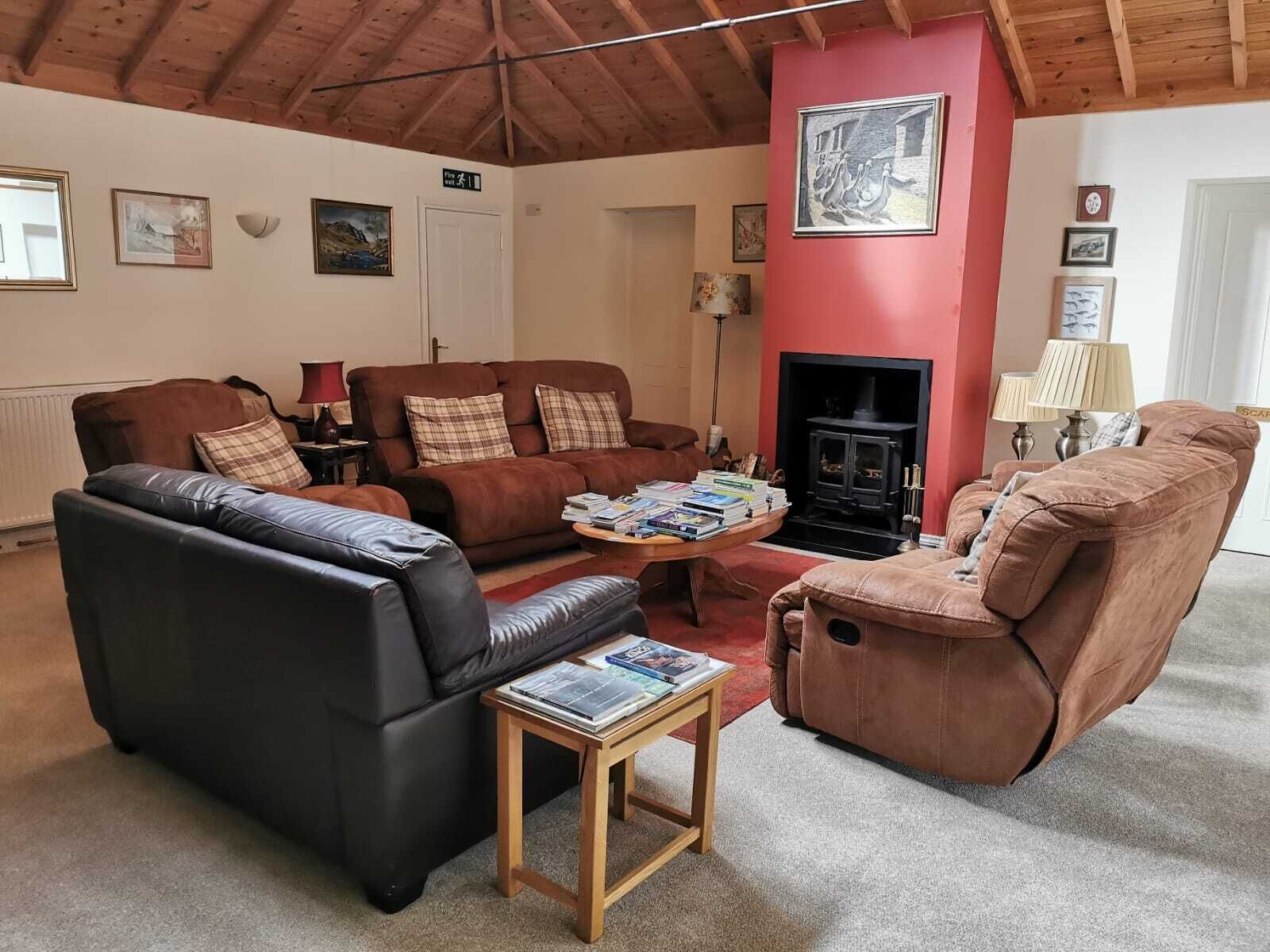 Uma sala de estar acolhedora com lareira, sofás de couro e uma mesa de centro com livros.