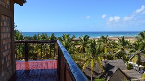 A wooden deck overlooking a beach with palm trees and a clear blue sky. - Gin and Jack Beach House (Inhambane)