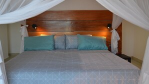 A bed with a geometric patterned bedspread, a wooden headboard, and two bedside lamps. - Gin and Jack Beach House (Inhambane)