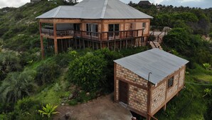 A two-story house with a balcony, surrounded by lush greenery and hills. - Gin and Jack Beach House (Inhambane)
