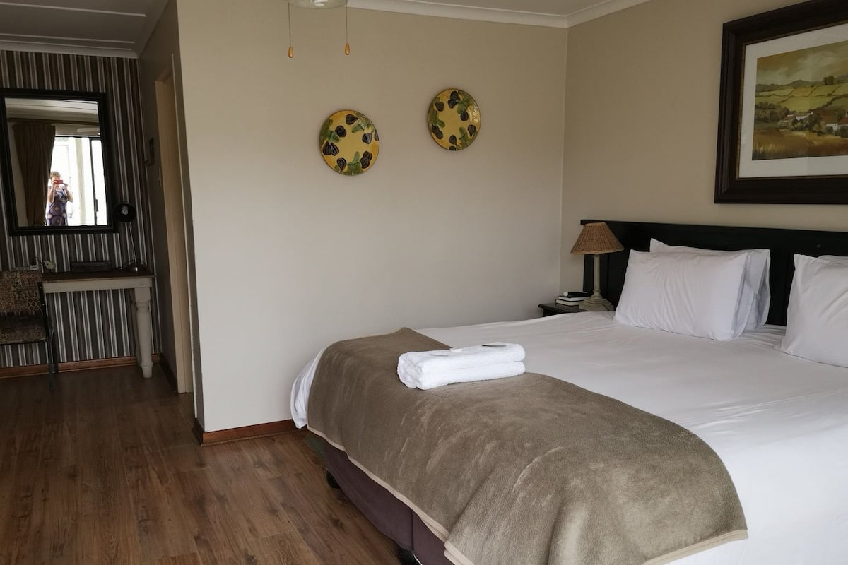 Ein Hotelzimmer mit einem großen Bett, einem Nachttisch, einer Lampe und zwei Wanddekorationen.