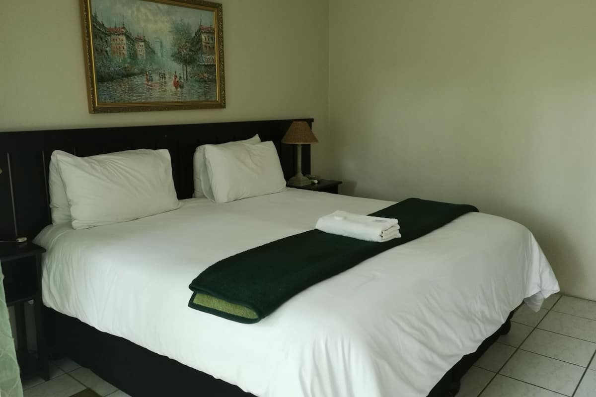 Ein Hotelzimmer mit einem großen Bett, einem Bild an der Wand und einem Nachttisch mit einer Lampe.