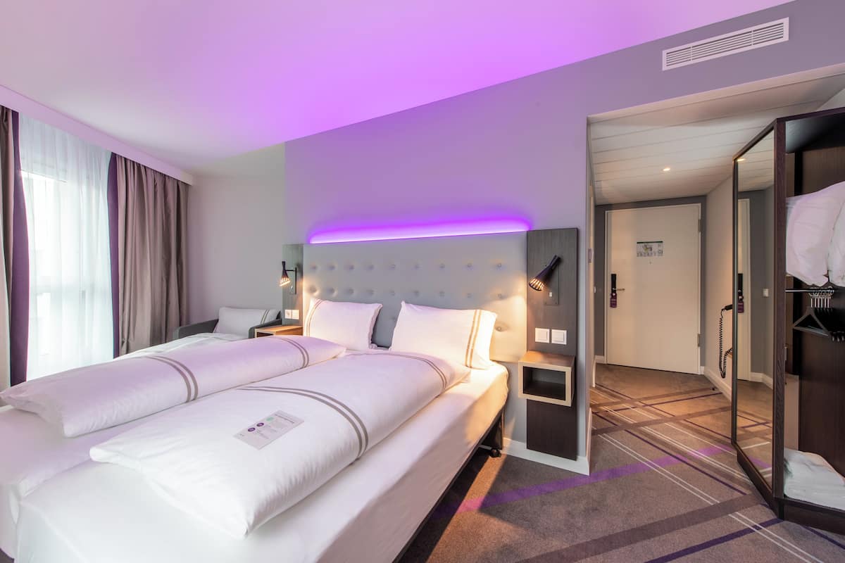 Camera d'albergo con un letto grande, comodini, un armadio e bagno visibile attraverso una porta aperta.