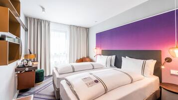 Habitación de hotel con dos camas, un escritorio, una silla, una lámpara y un amplio ventanal con cortinas.