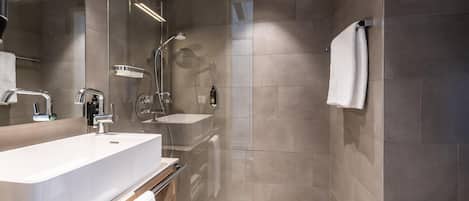 Un baño moderno con un lavamanos grande, un espejo y una zona de ducha.
