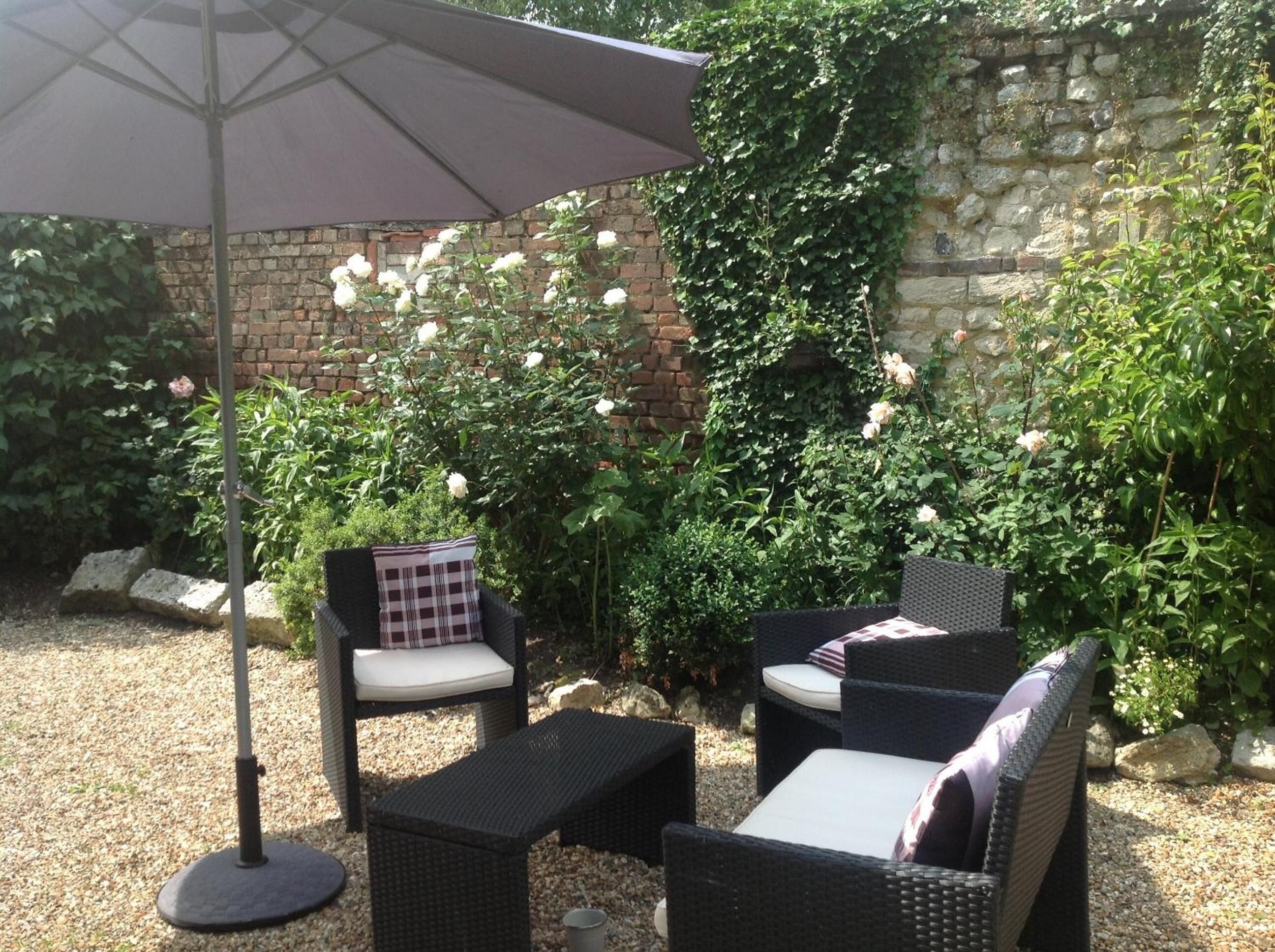 Un espace extérieur aménagé avec des meubles en osier et un grand parasol.