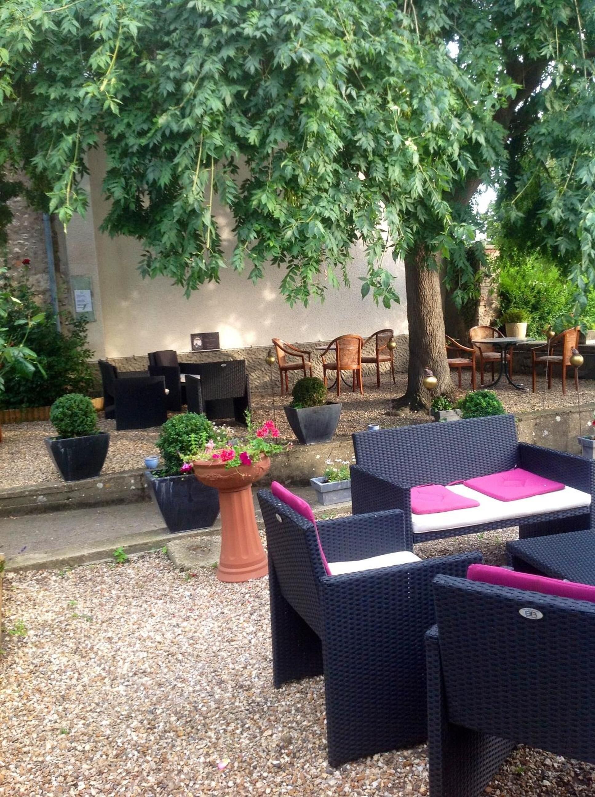 Un'area salotto esterna con mobili in vimini e piante in vaso.