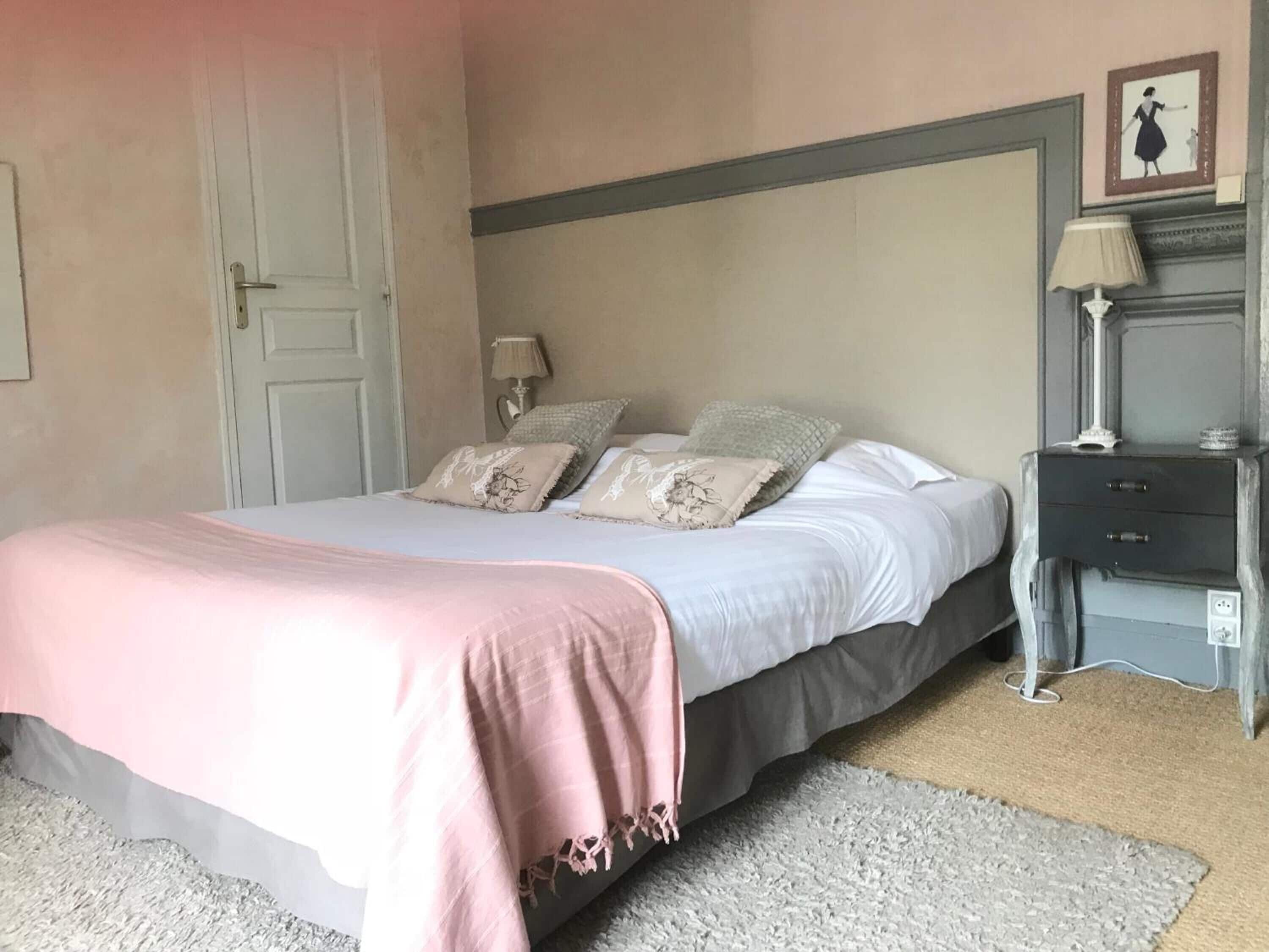 A bedroom with a bed, bedside tables, a lamp, and a door.