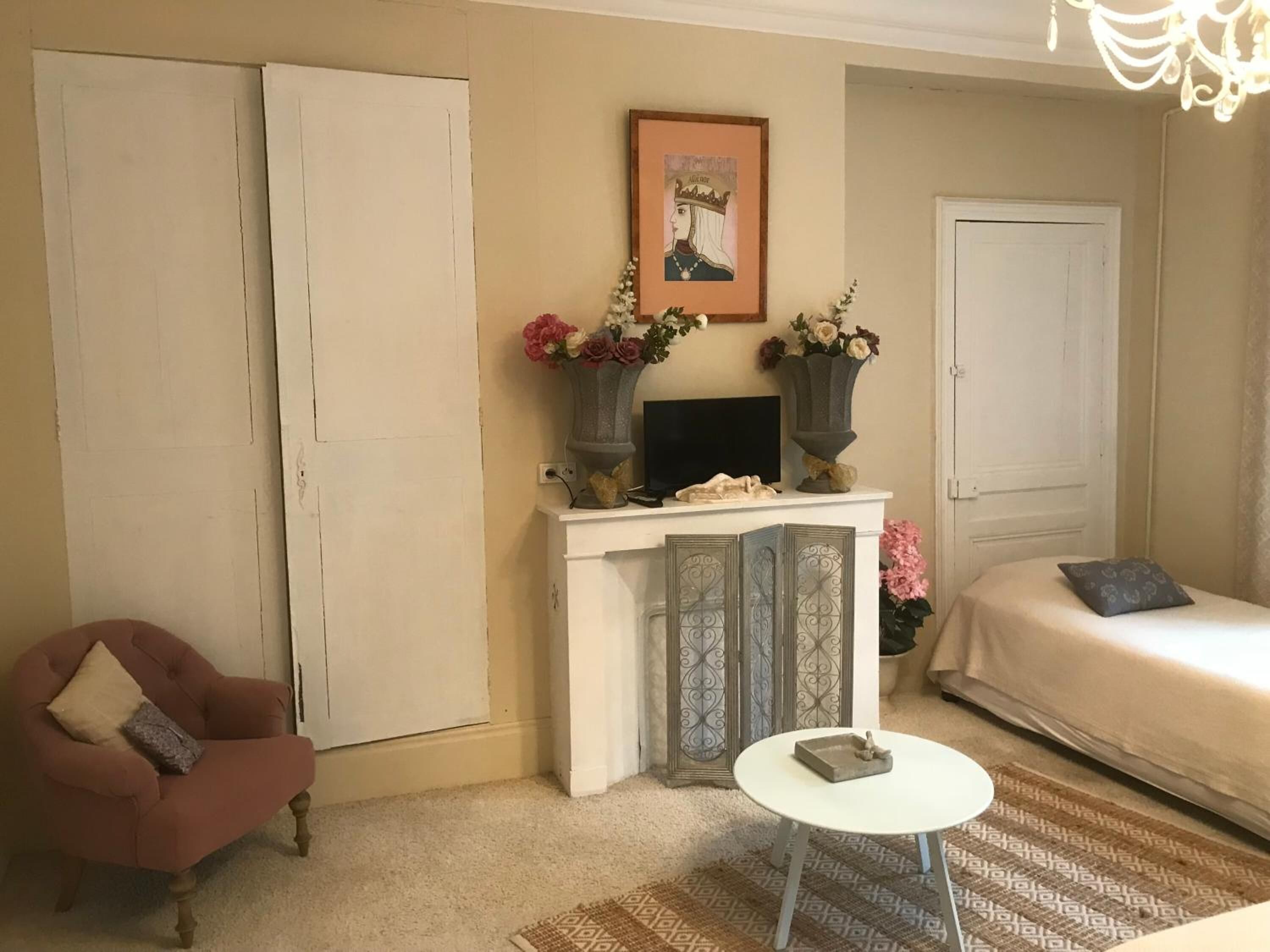 A cozy living room with a fireplace, a television, a bed, and a chair.