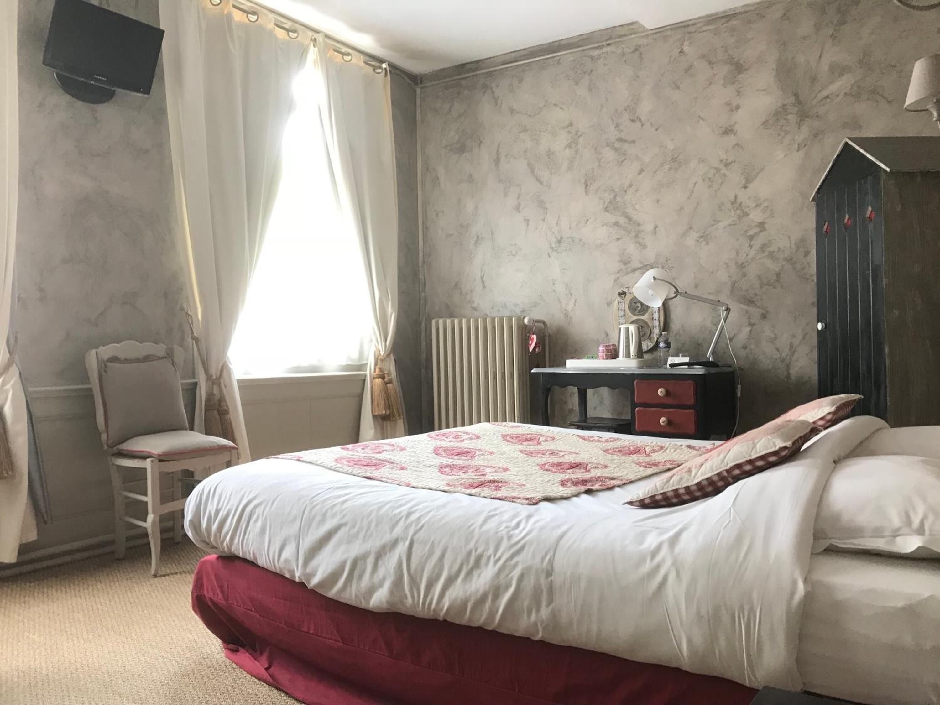 Une chambre à coucher avec un lit, une chaise, un bureau avec une lampe et un radiateur.