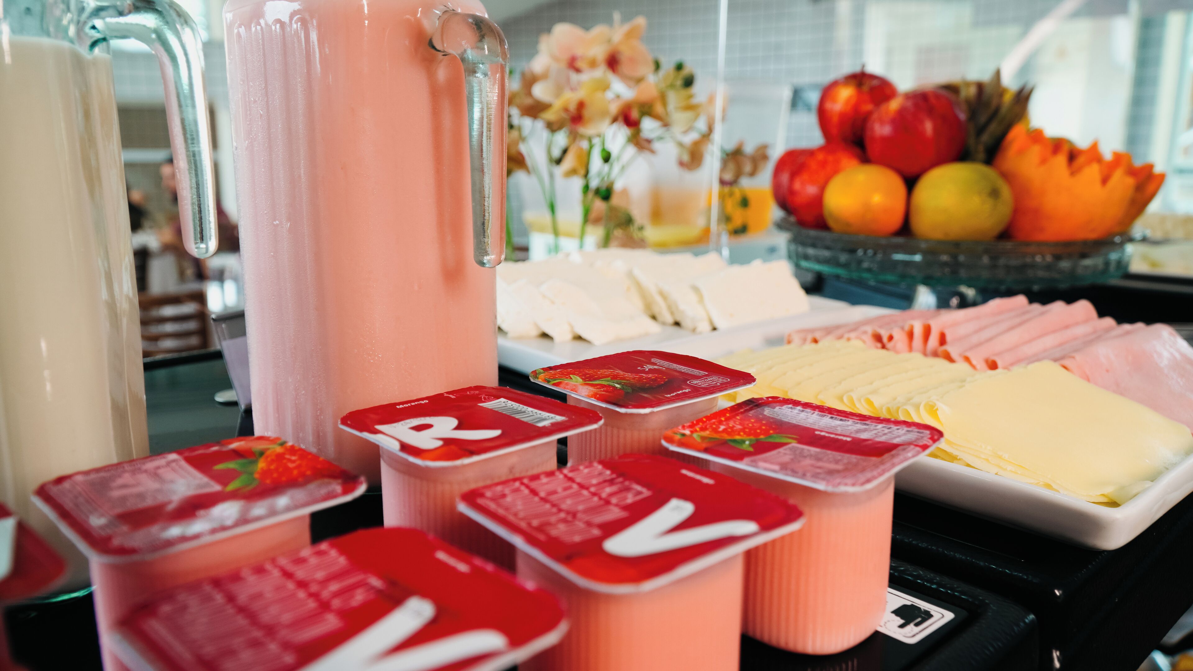 Un buffet proposant une variété d’aliments, notamment des yaourts, des fromages et des fruits.
