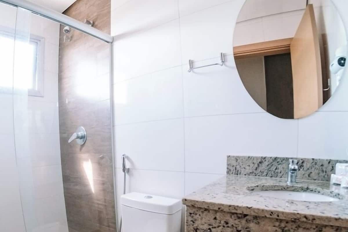 Une salle de bain moderne avec une douche à parois de verre, des toilettes, un lavabo doté d’un plan de travail en granit et un miroir au-dessus du lavabo.