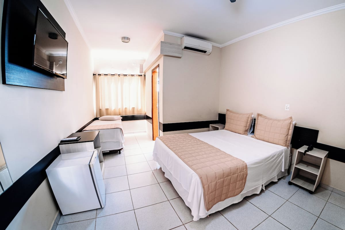 Une chambre d’hôtel moderne équipée d’un lit, de tables de chevet, d’un téléviseur et d’un appareil de climatisation.