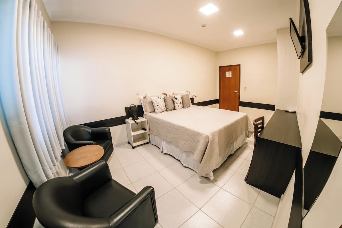 Une chambre d’hôtel comprenant un lit, un bureau, une chaise, une petite table et une armoire.