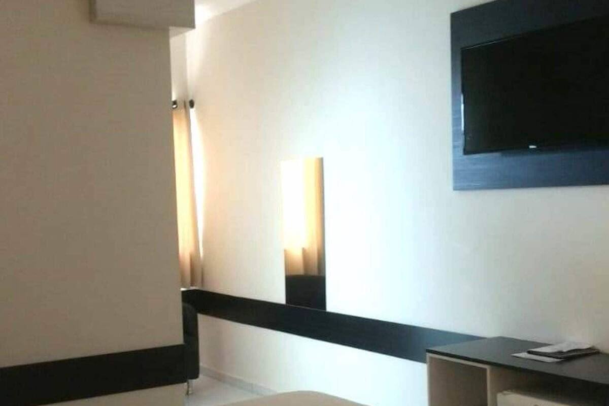 Une chambre d’hôtel équipée d’un lit, d’un bureau, d’une télévision à écran plat et d’un ventilateur de plafond.
