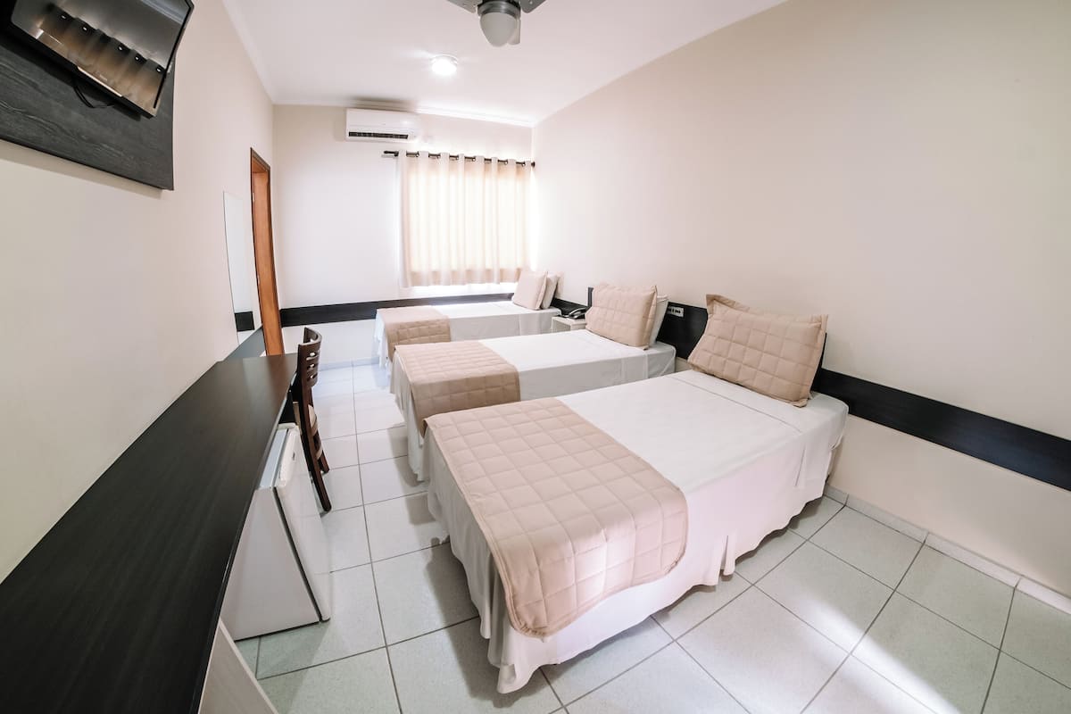 Une chambre d’hôtel avec deux lits, un bureau, une chaise, un miroir et un ventilateur de plafond.