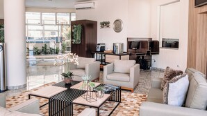 Un moderno vestíbulo de hotel con suelo a cuadros, asientos cómodos, una máquina de café y un televisor en una pared de madera.