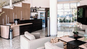 Un moderno vestíbulo con mostrador de recepción, zona de estar y vistas a la piscina.