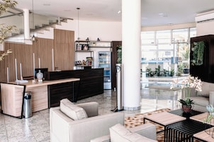 Um lobby moderno com balcão de recepção, área de estar e vista para a piscina.
