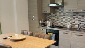 A modern kitchen with a dining area, featuring a wooden table, chairs, and a built-in oven. - Trastevere Sweet Rest (Rome)