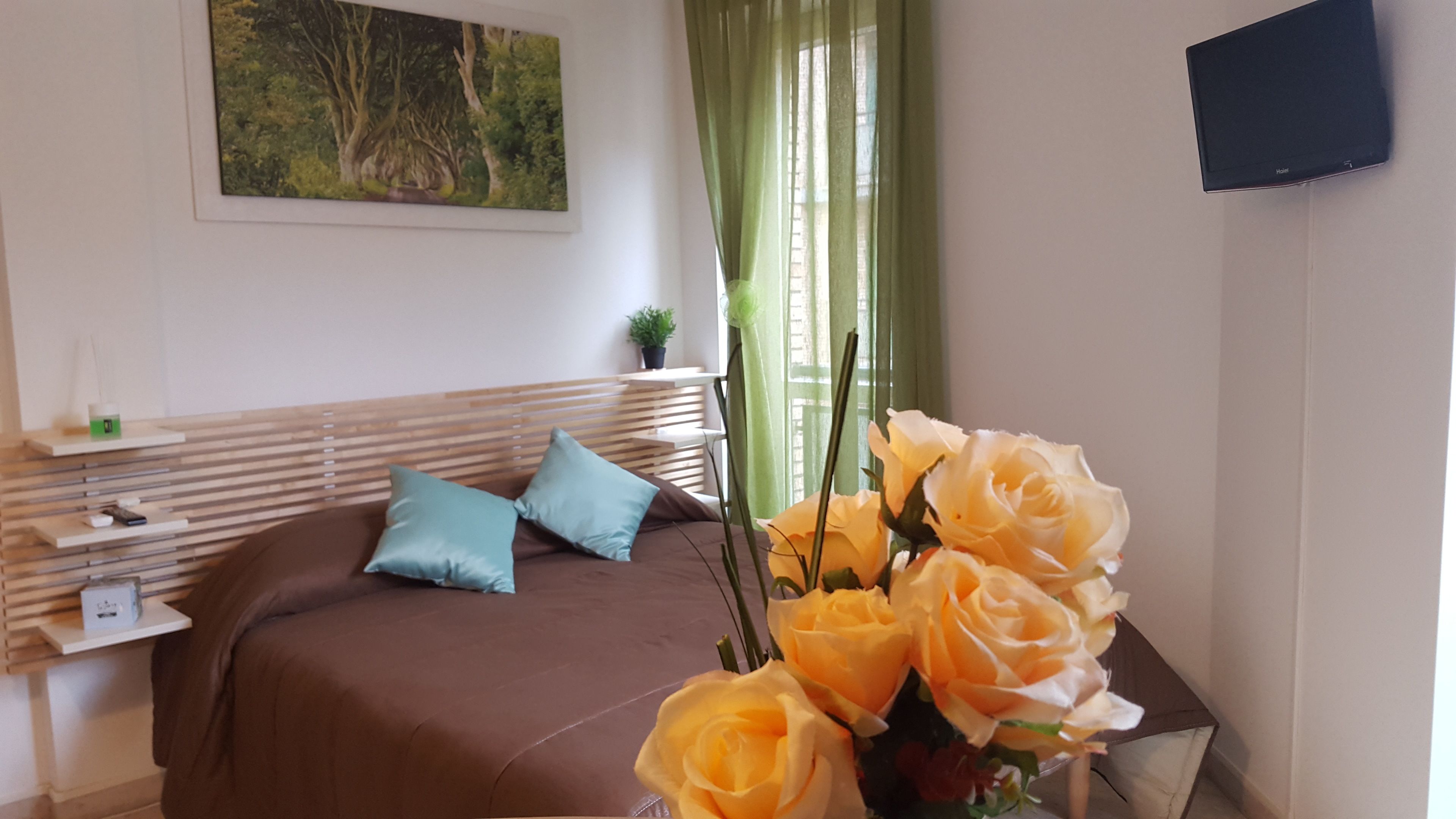 A bedroom with a bed, pillows, a bedside table, a TV, and a painting on the wall.