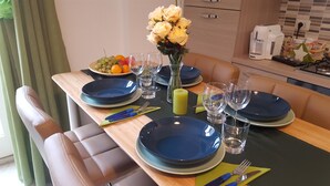 A dining table set with blue plates, clear glasses, and a vase of yellow flowers. - Trastevere Sweet Rest (Rome)
