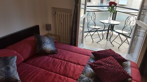 A room with a bed, a radiator, a window, and a balcony with a table and chairs. - Trastevere Sweet Rest (Rome)