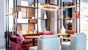 Un salon moderne comprenant un canapé, des fauteuils, une table basse et une bibliothèque.