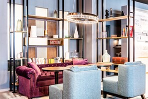 A modern living room with a sofa, armchairs, a coffee table, and a bookshelf.