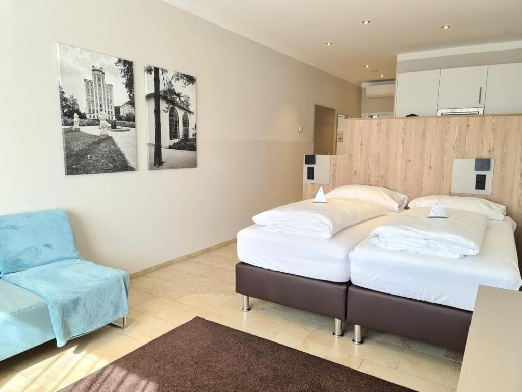 A modern hotel room with a large bed, a blue sofa, and two wall-mounted light fixtures.