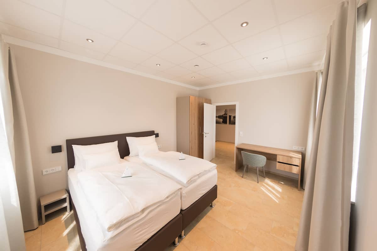 A hotel room with two beds, a desk, and a chair.