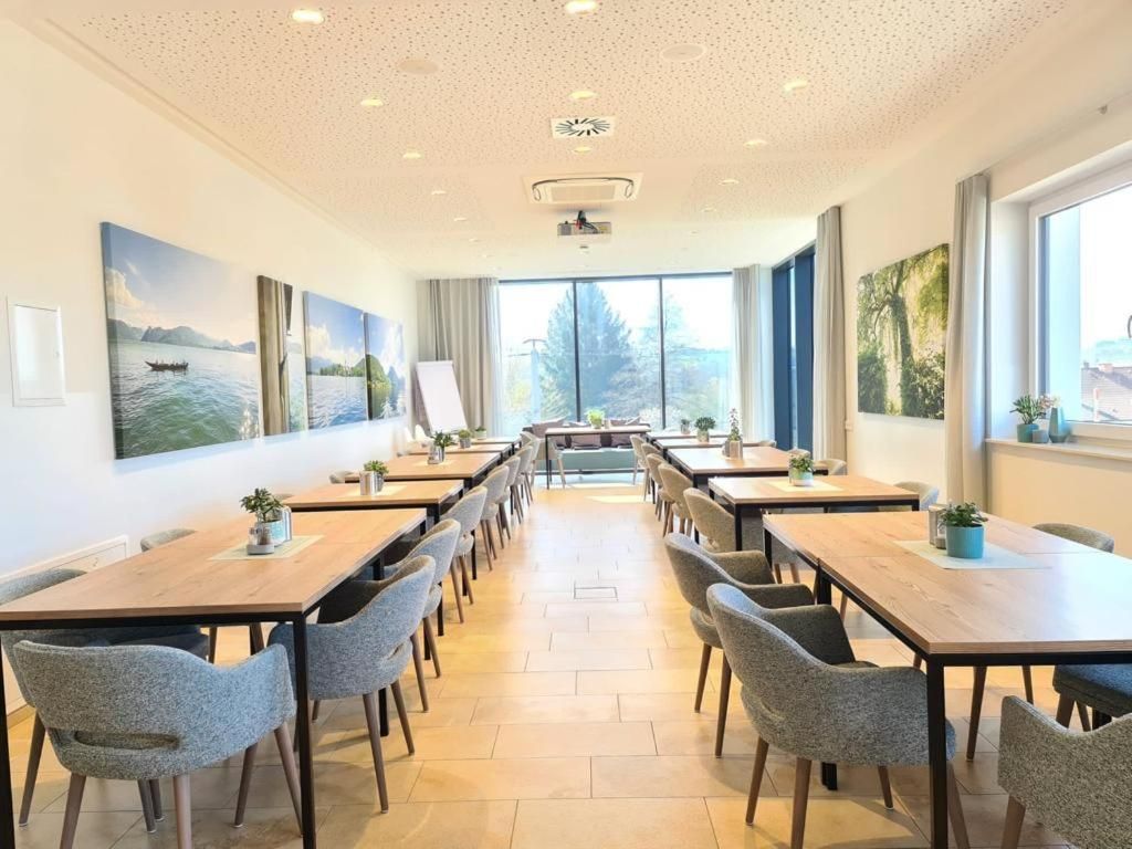 A conference room with multiple tables and chairs, large windows, and artwork on the walls.