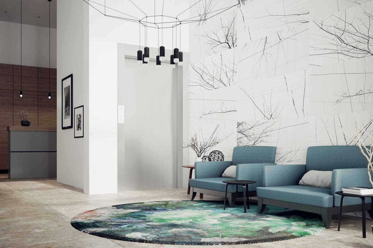 A modern living room with a sofa, a round rug, and a wall with abstract art.