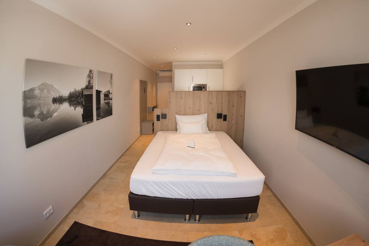 A modern hotel room with a large bed, a flat-screen TV, and artwork on the walls.