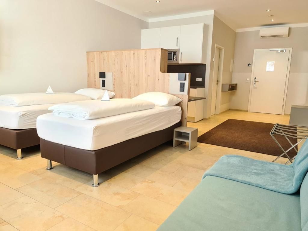 A hotel room with two beds, a kitchenette, a seating area, and a door.