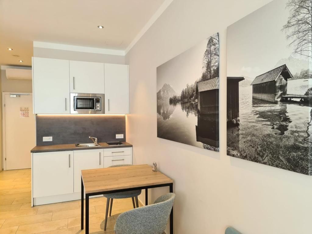 Une cuisine moderne avec des meubles blancs, un four à micro-ondes et un coin repas comprenant une table et des chaises.