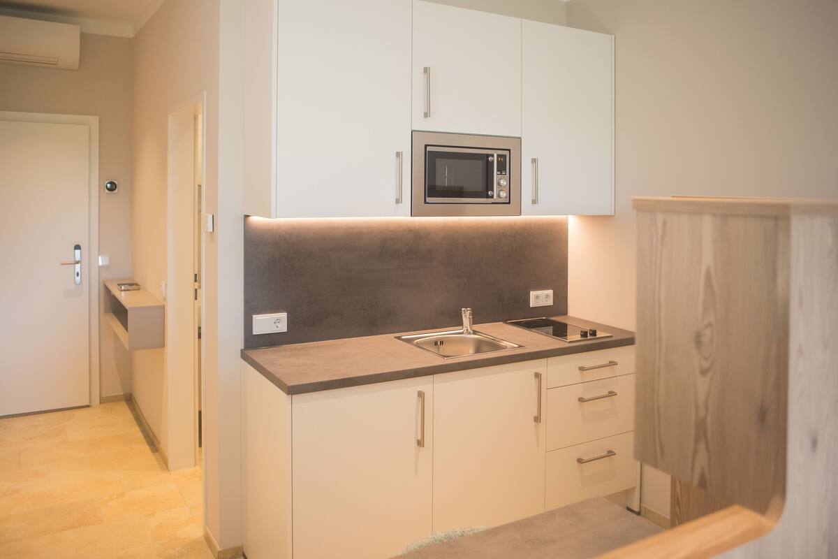 A compact kitchen with a microwave, sink, and cabinets.