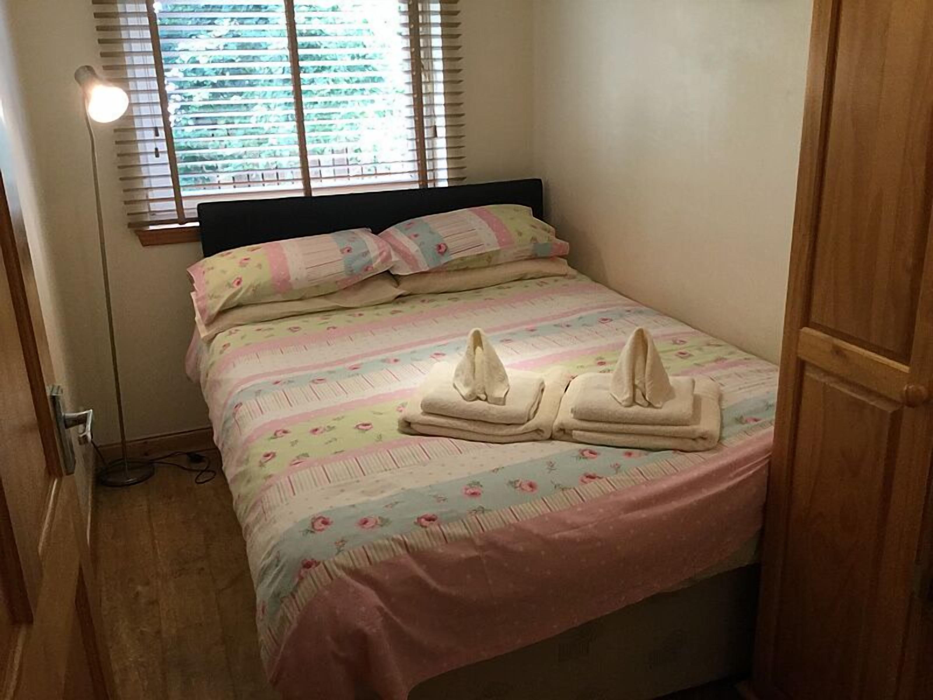 A bedroom with a bed, pillows, and a bedside lamp.