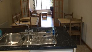 Una cocina compacta con lavabo, escurreplatos y zona de comedor con mesa y sillas.